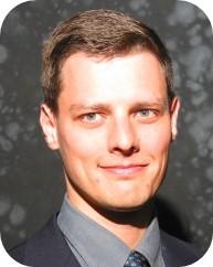 Agent John Balchunas, a smiling younger man with brown hair and green eyes